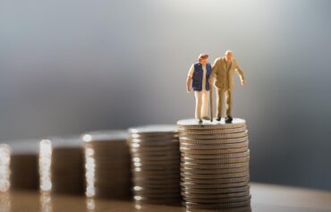 Ist die BVG Reform noch zu retten? Im Bild zum Artikel von Centre Patronal wird ein Miniatur-Paar auf einer Säule aus Münzen gezeigt.