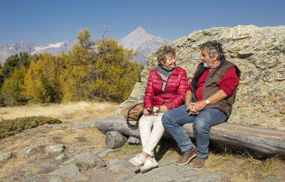 Bild zeigt ein Rentner-Paar vor der Bergkulisse des Bietschhorns, Wallis. Renteninitiative: Unverständlicher Salto rückwärts. Die Renteninitiative hat trotz ihrer Mängel den Vorzug, dass sie einen Mechanismus zur Schuldenbremse der AHV vorsieht, der das Verhältnis zwischen der Dauer des Erwerbsleben und der Dauer des Ruhestands berücksichtigt. Die Forderung nach einem Gegenentwurf, die am 5. Juni vom Nationalrat unterstützt wurde, war daher vollkommen gerechtfertigt, und die Kehrtwende der mit dieser Aufgabe betrauten Kommissionsmitglieder ist unverständlich.